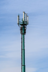 Telecommunications antennas on the telecommunications tower with cloudy blue sky in the background