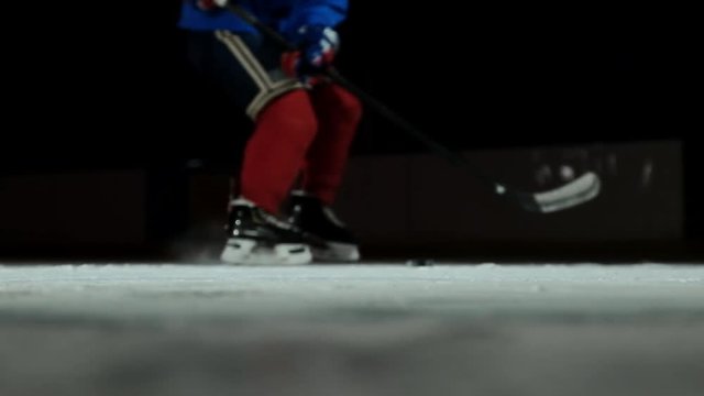 Close-up slow motion hockey puck and flying snow, hockey player picks up the puck stick