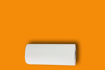 One full roll of white soft paper towel or paper for toilet on orange table with copy space for your text. Top view