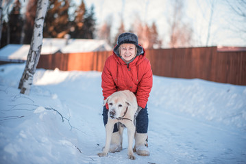 the woman of 50 years embraces the old dog of a Labrador on snow