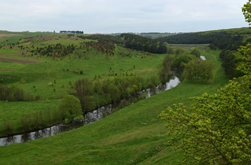 Ukrainian landscape in spring. Fields covered with green grass on the banks of the River skyline