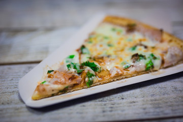 A slice of pizza close-up, appetizing pizza filling, cheese. Hand takes a separate piece of pizza