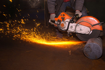 Obraz premium Closeup Worker saws metal with a large circular saw in the hands of the factory workshop, sparks