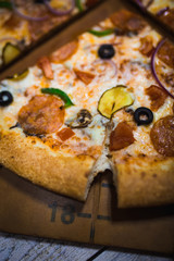A slice of pizza close-up, appetizing pizza filling, cheese. Hand takes a separate piece of pizza