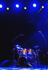Naklejka na ściany i meble Empty illuminated stage with drumkit, guitar and microphones