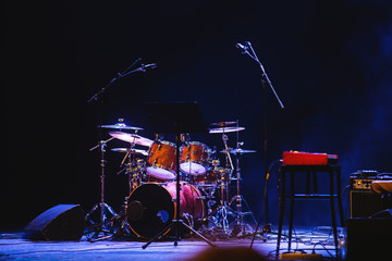 Empty illuminated stage with drumkit, guitar and microphones