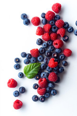Raspberries and blueberries isolated on white background with copy space