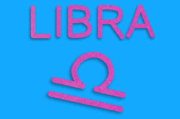 Symbol of astrological sign and word libra cut out of purple paper on blue table. Top view. Horoscope concept