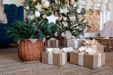 Fototapeta na wymiar Branches of a Christmas tree in a wicker basket. Gifts in Kraft paper packaging with white bows of ribbons.