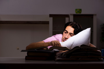 Obraz premium Male handsome student preparing for exams late at home