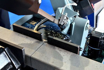 Automatic CNC band saw cutting  tool steel bar by automatic feed. Modern industrial technology. Shooting in real conditions, a little blurry and maybe grain