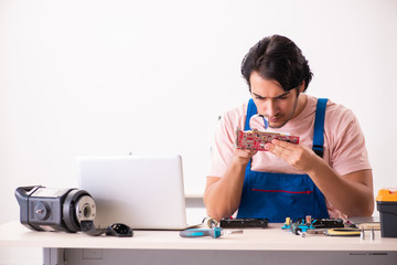 Young male contractor repairing computer