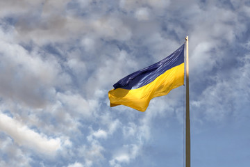 Blue and yellow Ukrainian national flag on a flagpole against a blue cloudy sky, copy space for text. presidential elections in Ukraine 2019.