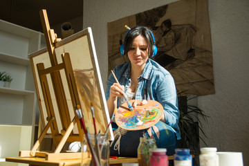 Young woman painting and listens to music