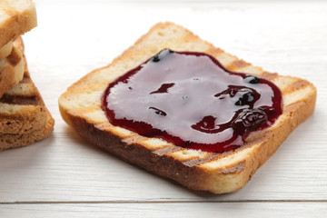 toasts with jam. fried crispy toasts with red jam on a white wooden table.