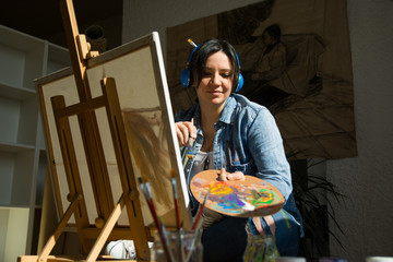 Woman painting with earphones on her ears