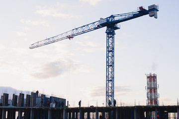Fototapeta na wymiar Construction crane on the construction site. Under construction concrete building.