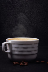 Cup of hot coffee on black background
