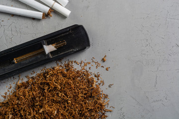 Making cigarettes with tobacco rolling machine on a gray stone table, top view, copy paste place