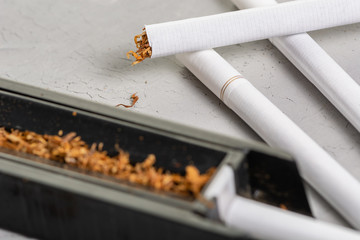 Cut and dried tobacco leaves. A device for making cigarettes at home. Homemade Tobacco Cigarette, copy paste space, in the gray background