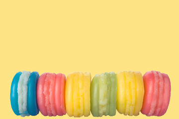 Colorful macaroni cookies on yellow lemon background