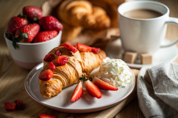 Croissant with cream cheese, strawberries for breakfast