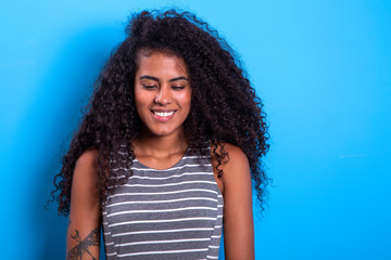 Portrait of smiling black woman with afro hairstyle on blue background.