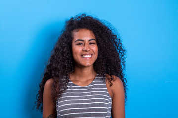 Portrait of smiling black woman with afro hairstyle on blue background.