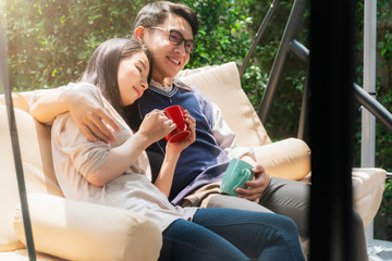 Fototapeta premium sweet and lovey asian couple husband and wife with hot drink talk together with happiness and peaceful home interior background
