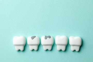 Healthy white teeth and tooth with caries on green mint background. Copy space for text.