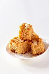 Basbousa or namoora traditional arabic semolina cake with cashew nuts and syrup Isolate white background Selective focus.