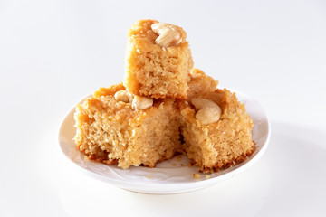 Basbousa or namoora traditional arabic semolina cake with cashew nuts and syrup Isolate white background Selective focus.