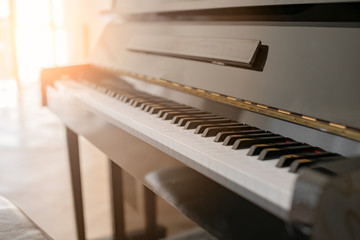 black shiny piano with sun light from white curtain window