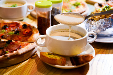 Bowl on a table with mushroom soup and a spoon hovering above