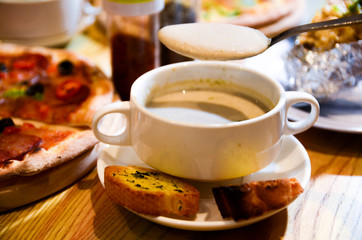 Bowl on a table with mushroom soup and a spoon hovering above