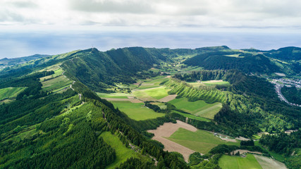 Fototapeta na wymiar Aerial view on scenic landscape of volcano and green fields around it. Special shape of ground. Top view from drone. Azores islands, Sao Miguel, Portugal.