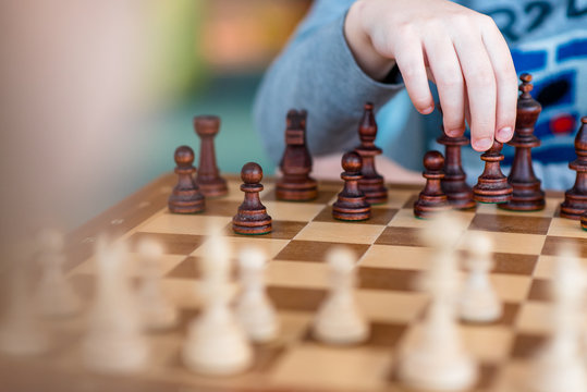 The chess-playing boy, subling the pawn on the chessboard