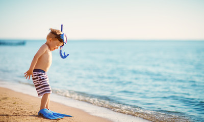 three years old boy playing at the beach with swimming ring