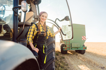 Bäuerin steht vor dem Traktor auf dem Kornfeld während der Ernte