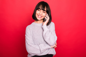 Pretty young woman calling by phone against red background