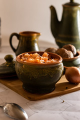 sauerkraut with boiled potatoes in earthenware on a light background