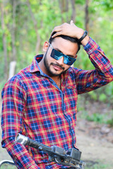 man model holding his hair with left hand and wearing a sun glass with a bike