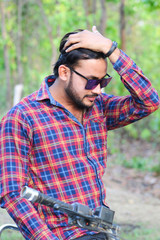 man model holding his hair with left hand and wearing a sun glass with a bike