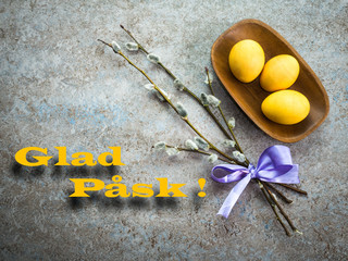 Happy Easter greeting card. Colored Easter eggs in wooden plate on the stone background. Easter concept in Swedish. Glad Påsk!