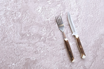 Top view of concrete surface with camping fork and knife with horn handle