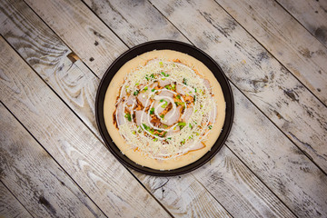 Round pizza dough is in the pan. The process of cooking pizza, stacking ingredients on the dough.