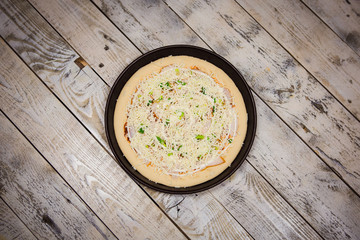 Round pizza dough is in the pan. The process of cooking pizza, stacking ingredients on the dough.