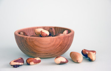 Brazil nuts in a wooden bowl on a blue background. Copy space