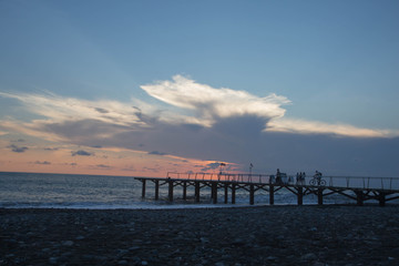Fototapeta premium sun setting over Batumi beach Jetty, as powerful waves roll in, and a very colorful sky is reflected on the beach