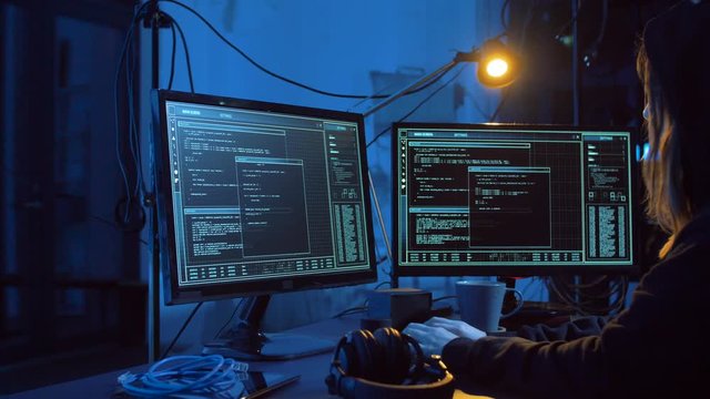 cybercrime, hacking and technology concept - female hacker in dark room creating code or using computer virus program for cyber attack